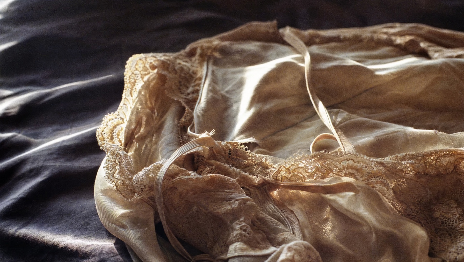 Soft-focus photograph of white and gold lace lingerie in low light